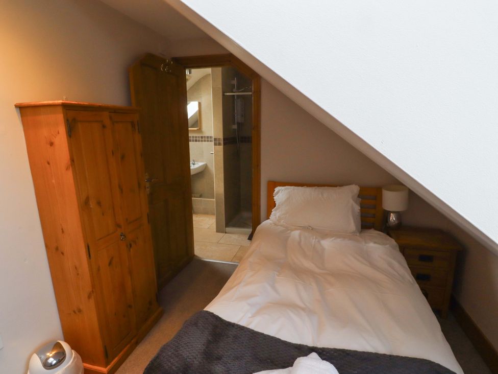 A bedroom with a single bed and wardrobe at Heather Cottages - Grey Seal in Bamburgh