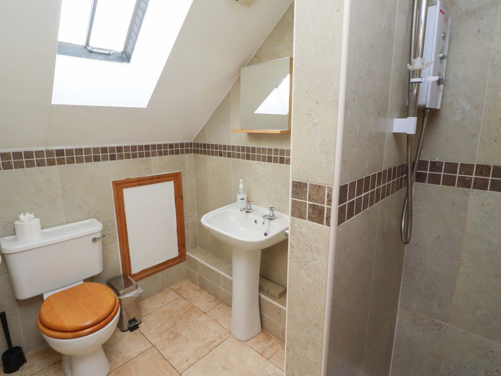 A bathroom with a toilet, sink, and shower at Heather Cottages - Grey Seal, Bamburgh