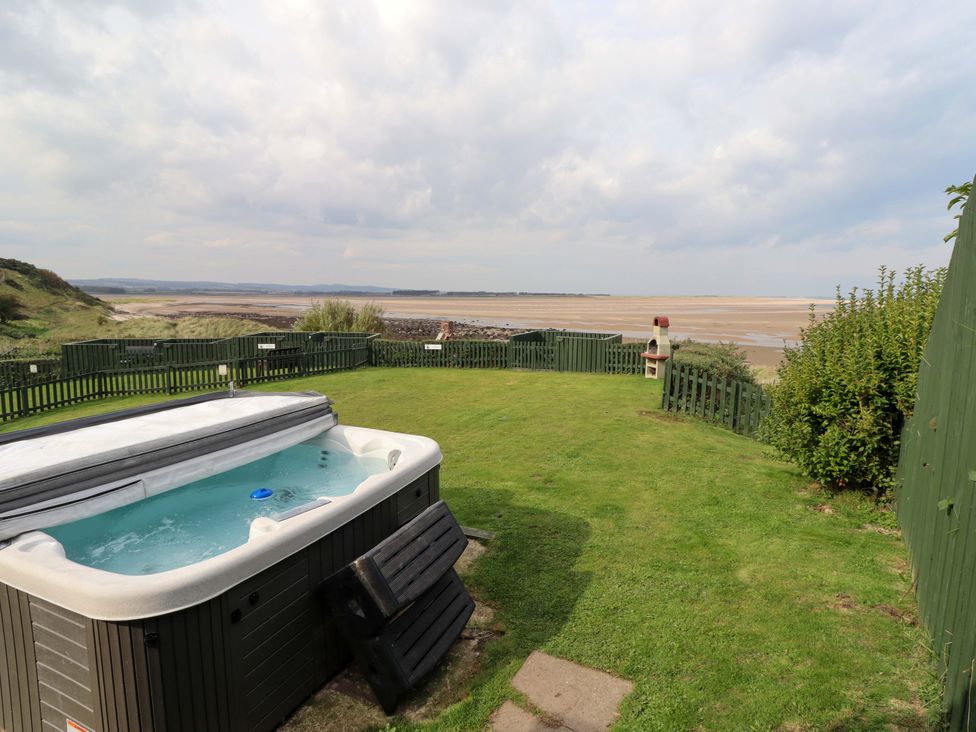 An outdoor space with a hot tub and sea view at Heather Cottages - Grey Seal in Bamburgh
