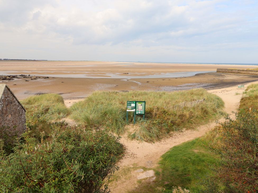A beach with sand and signs at Heather Cottages - Grey Seal in Bamburgh