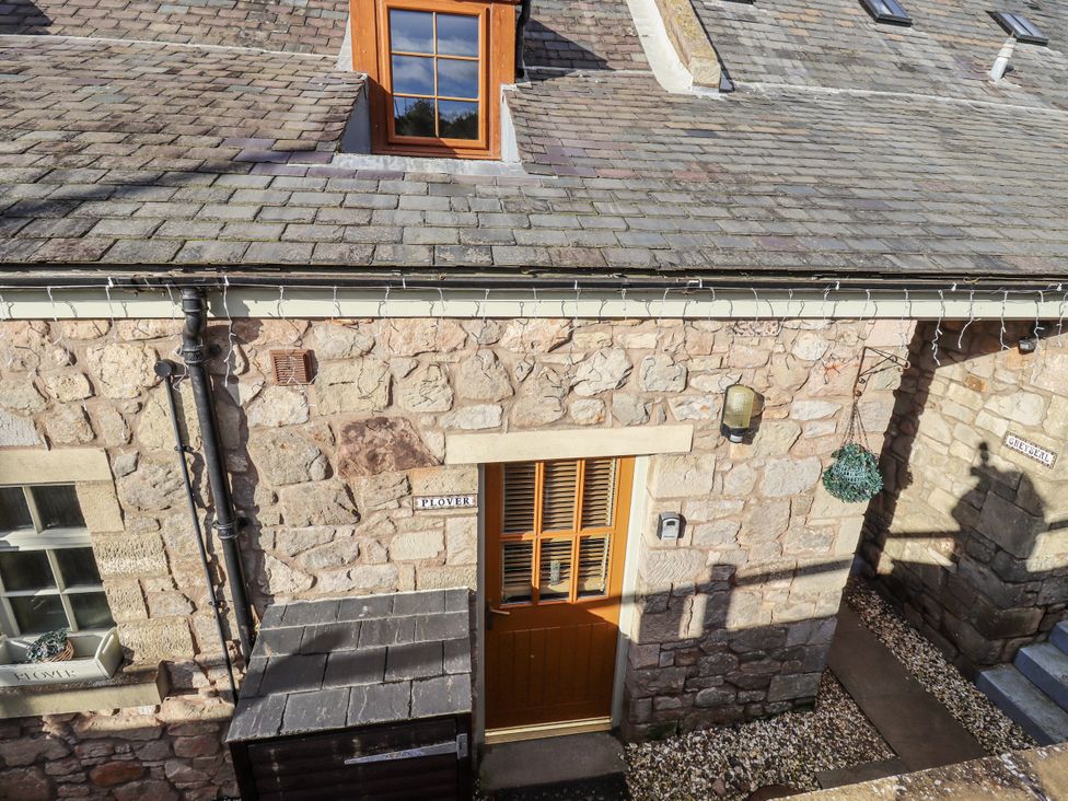 A stone exterior with a door and window at Heather Cottages - Plover in Bamburgh