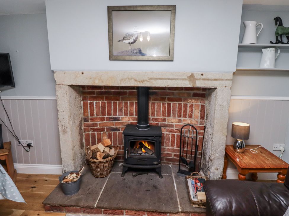 A living room with a fireplace and wood stove at Heather Cottages - Plover in Bamburgh