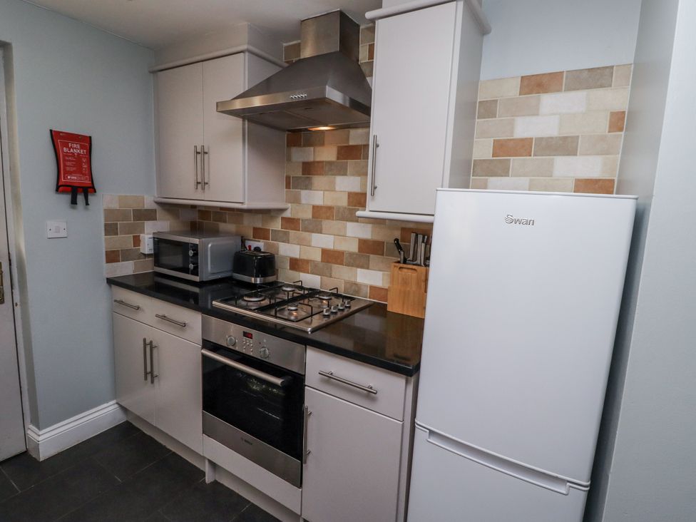A kitchen with a stove and refrigerator at Heather Cottages - Plover in Bamburgh