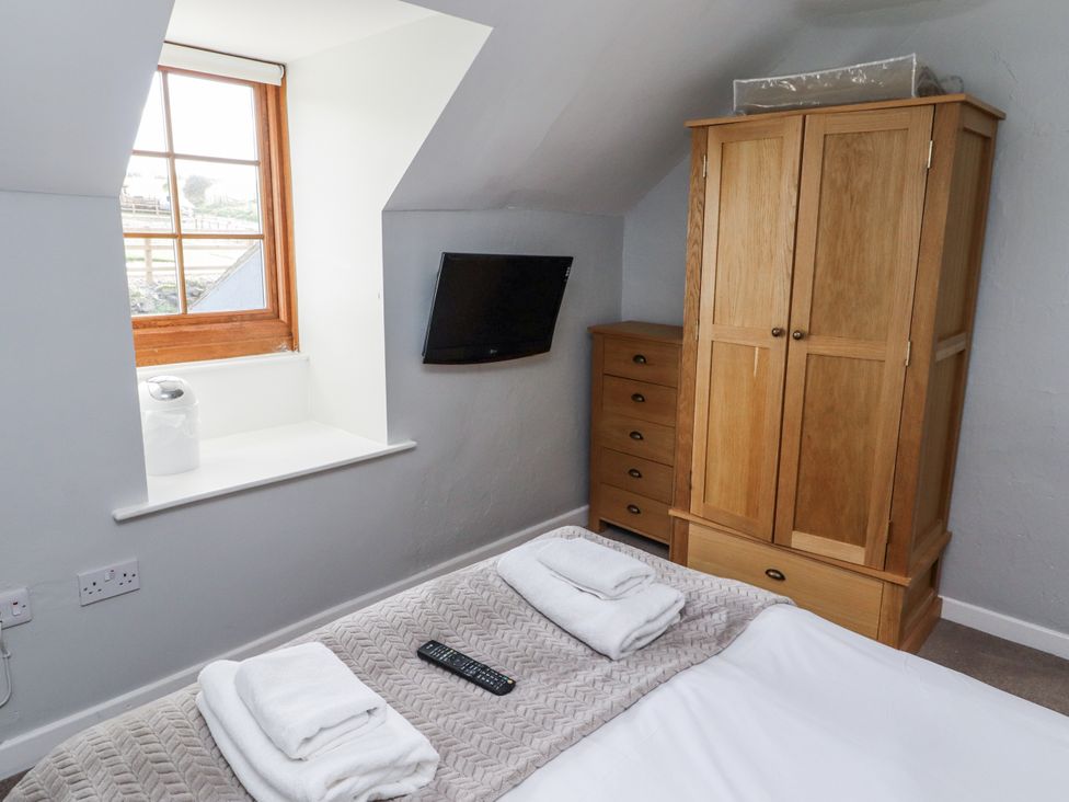 A bedroom with a bed and wardrobe at Heather Cottages - Plover in Bamburgh