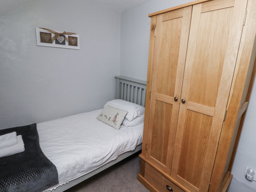 A bedroom with a bed and wardrobe at Heather Cottages - Plover in Bamburgh