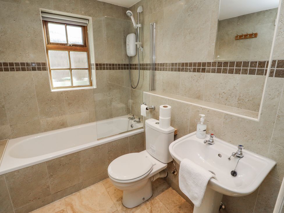 A bathroom with a bathtub, toilet, and sink at Heather Cottages - Plover in Bamburgh