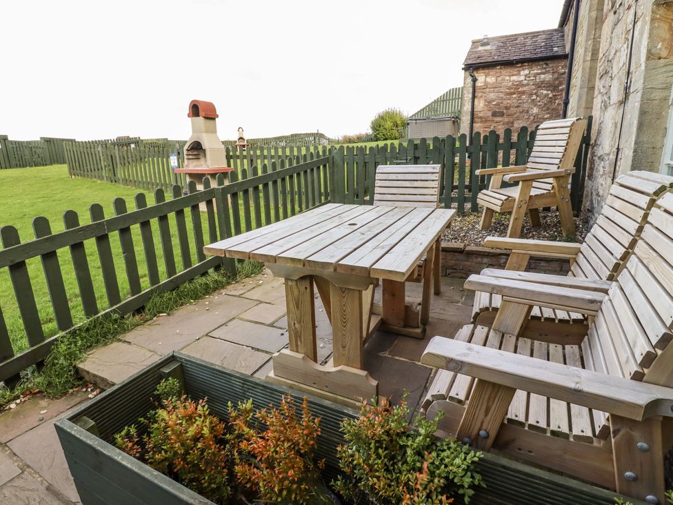 An outdoor area with wooden furniture and a fireplace at Heather Cottages - Plover in Bamburgh