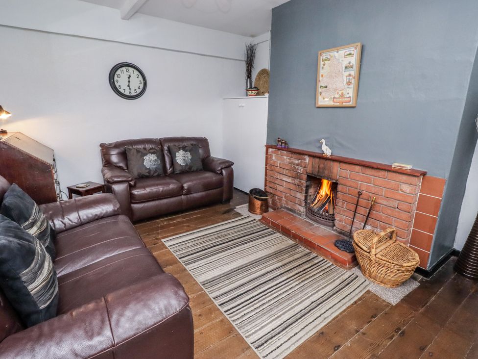 A living room with a fireplace and a sofa at Kittiwake Cottage, Budle Bay