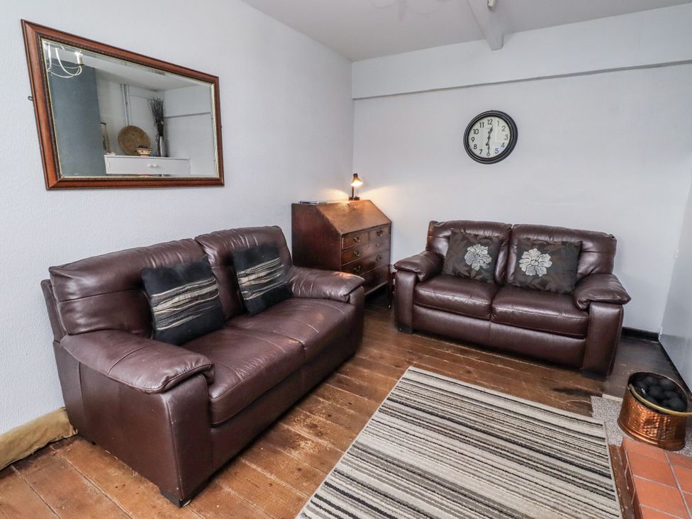 A living room with brown sofas and a mirror at Kittiwake Cottage, Budle Bay