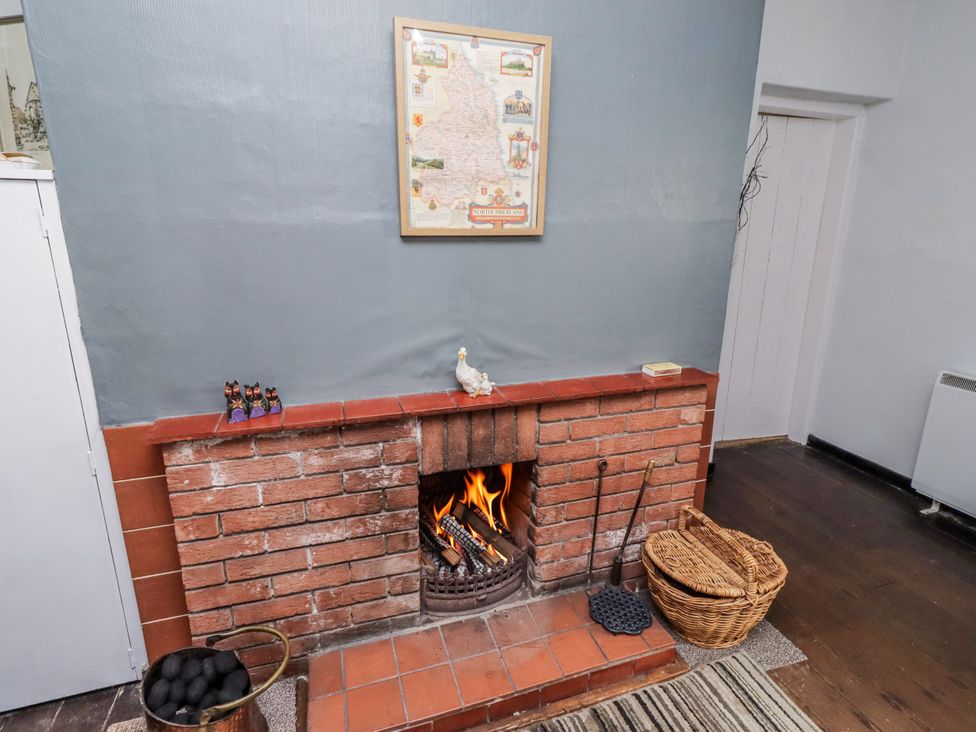 A living room with a fireplace and a map at Kittiwake Cottage, Budle Bay