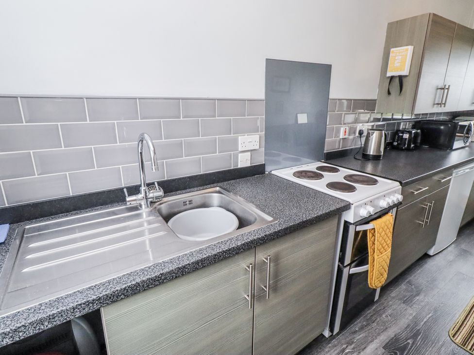 A kitchen with a sink and stove at Kittiwake Cottage, Budle Bay
