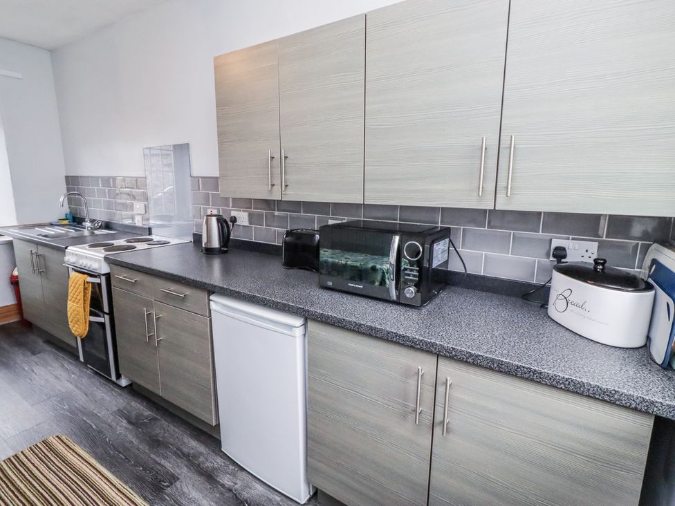 A kitchen with appliances and cabinets at Kittiwake Cottage, Budle Bay