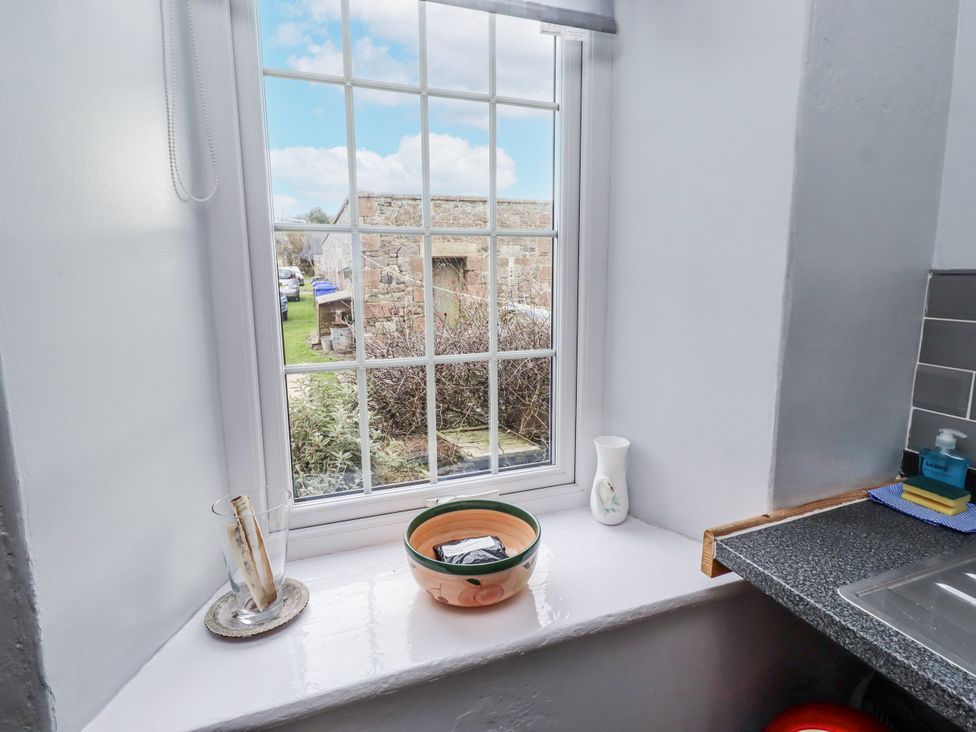 A kitchen window with a bowl and water pitcher at Kittiwake Cottage, Budle Bay