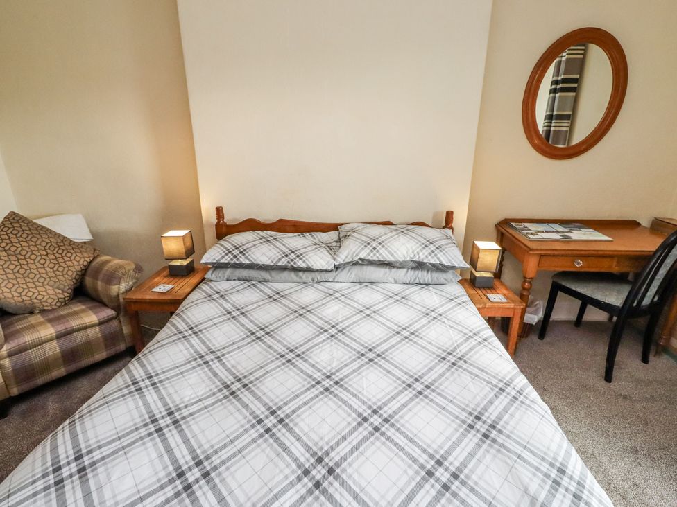 A bedroom with a bed, table, chairs, and lamp at Kittiwake Cottage, Budle Bay Bamburgh