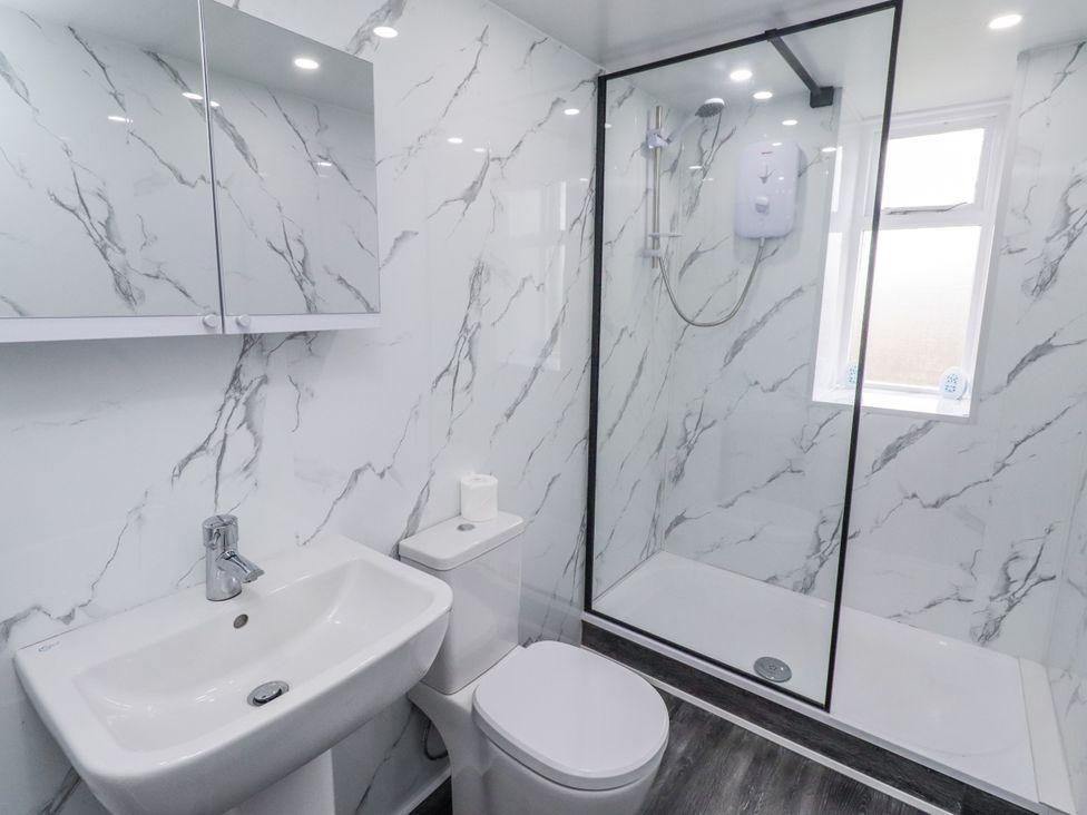 A bathroom with a sink, toilet, and shower at Kittiwake Cottage, Budle Bay Bamburgh