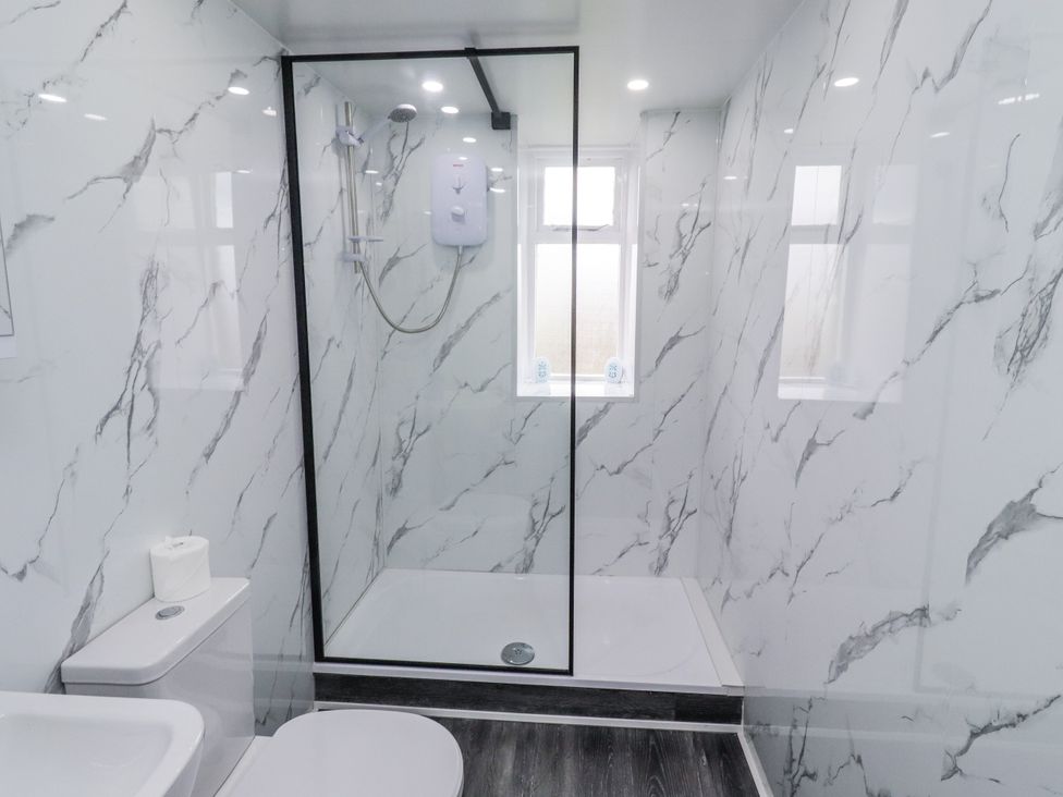 A bathroom with a shower and toilet at Kittiwake Cottage, Budle Bay Bamburgh
