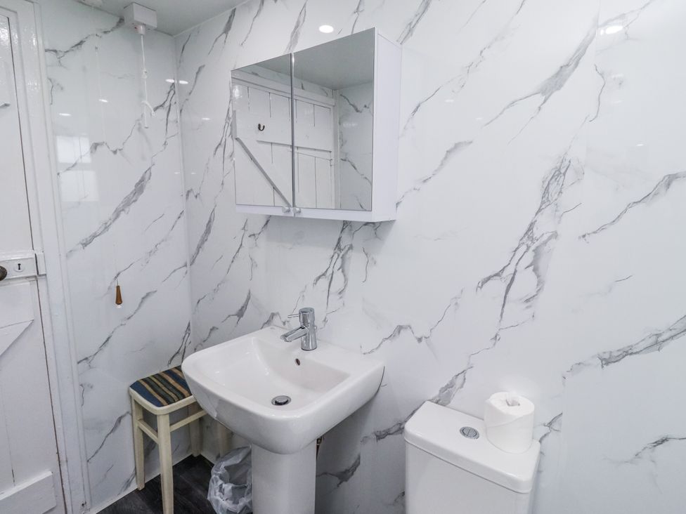 A bathroom with a sink, toilet and mirror at Kittiwake Cottage, Budle Bay