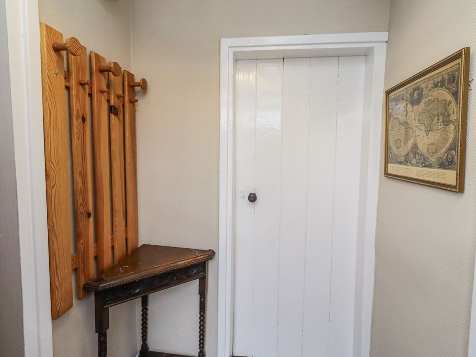 A hallway with a coat rack and a wooden table at Kittiwake Cottage, Budle Bay