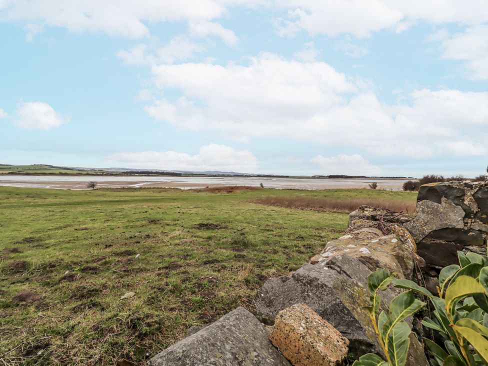 A view of a grassy area and water at Kittiwake Cottage, Budle Bay