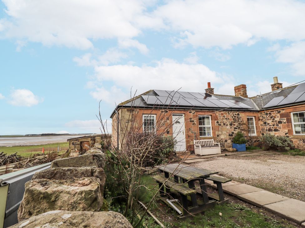 An outdoor view of a house with solar panels and a garden at Kittiwake Cottage, Budle Bay
