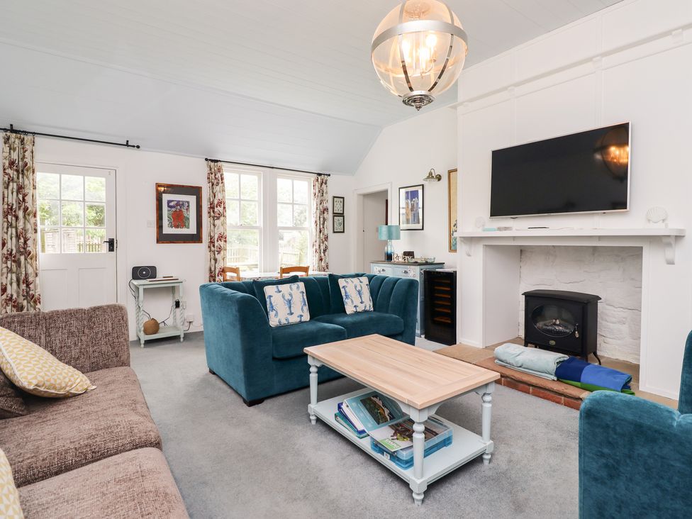 A living room with blue sofas a coffee table a wall mounted tv and a fireplace at Salty Dog in Bamburgh