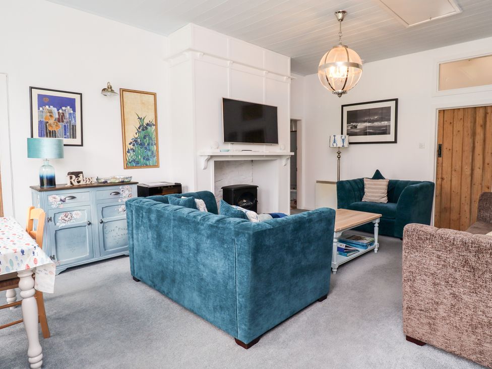 A living room with blue sofas a wooden coffee table and a TV above a fireplace at Salty Dog in Bamburgh