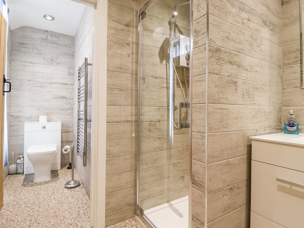 A bathroom with a toilet a glass shower enclosure and a sink with soap at Salty Dog in Bamburgh