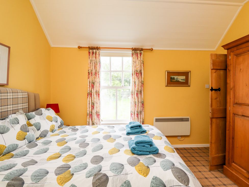 A bedroom with a bed near a window and wooden wardrobe at Salty Dog in Bamburgh