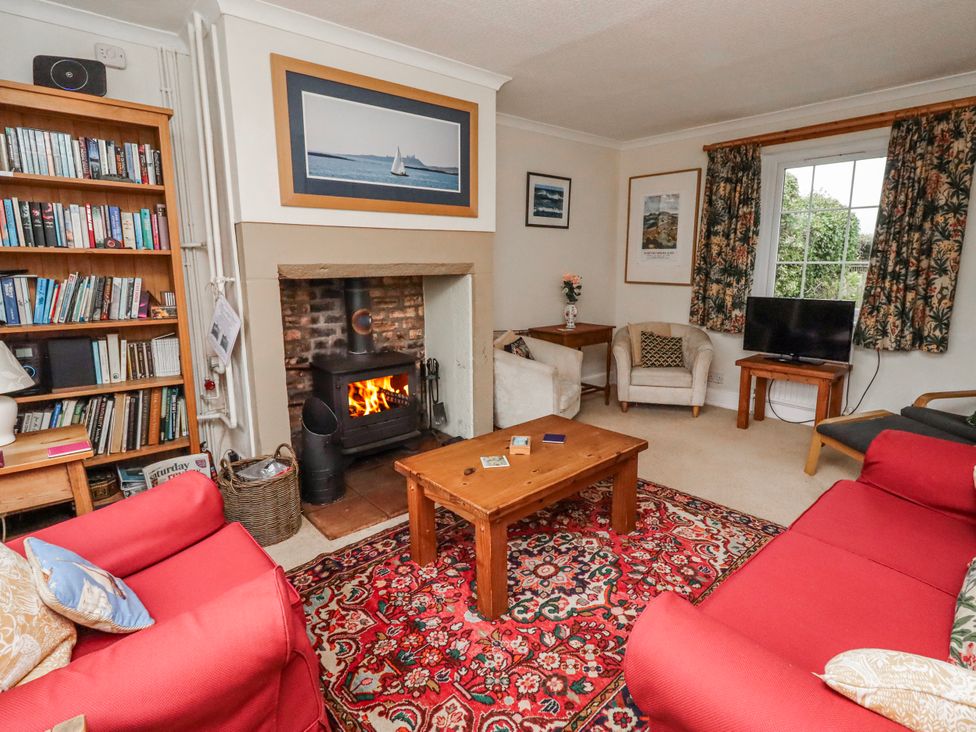 A living room with a fireplace and bookshelf at St Marys Cottages No4 Low Newton-by-the-Sea