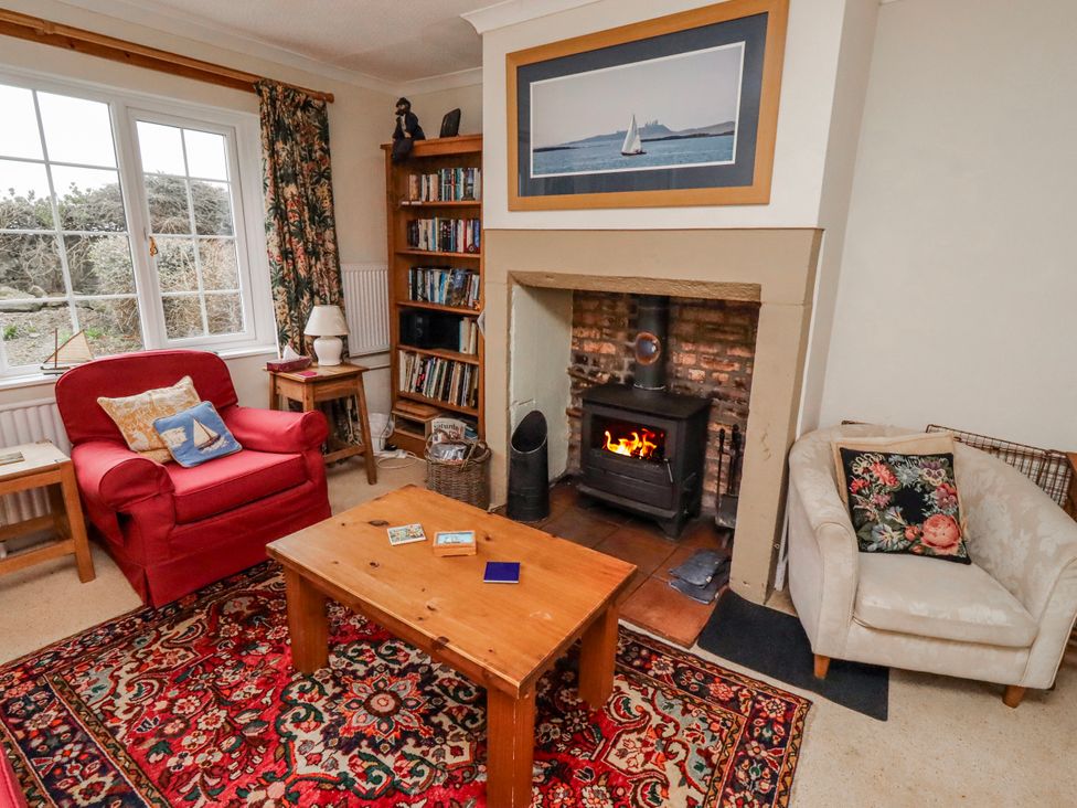 A living room with a stove and bookshelf at St Marys Cottages No4 Low Newton-by-the-Sea