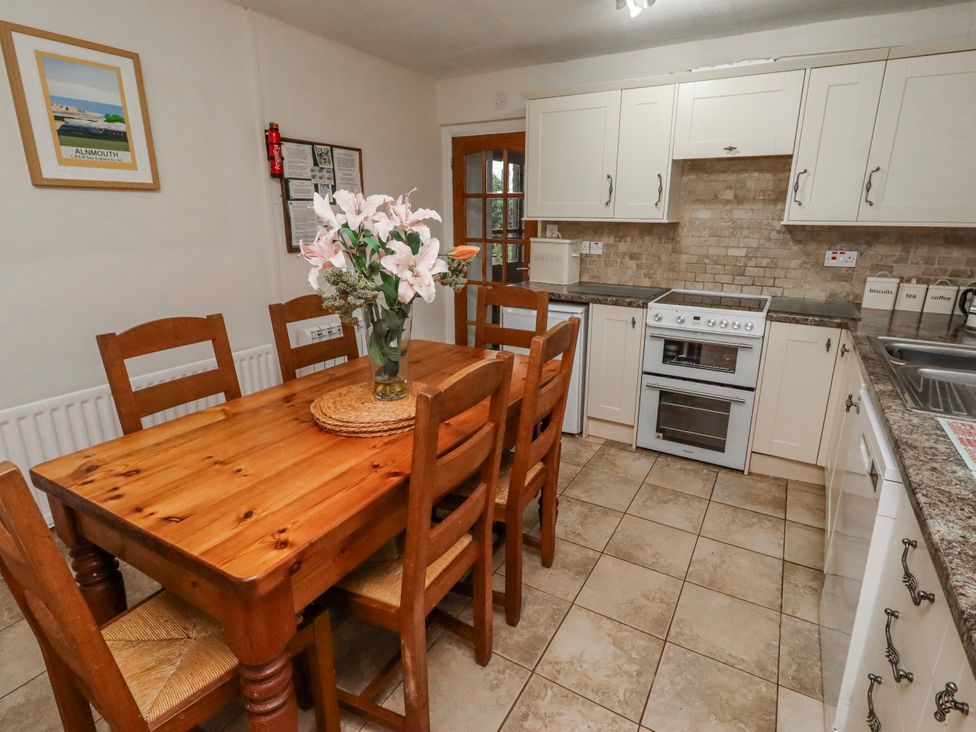 A kitchen with a wooden dining table and chairs at St Marys Cottages No4 Low Newton-by-the-Sea