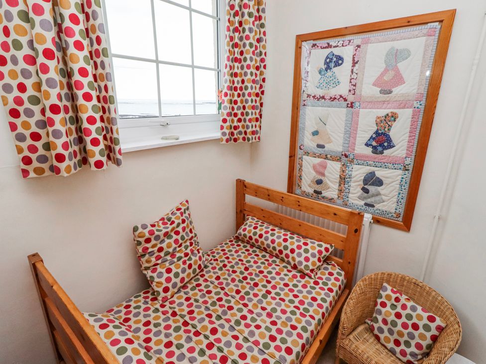 A bedroom with a bed, quilt on the wall and window at St Marys Cottages No4 Low Newton-by-the-Sea