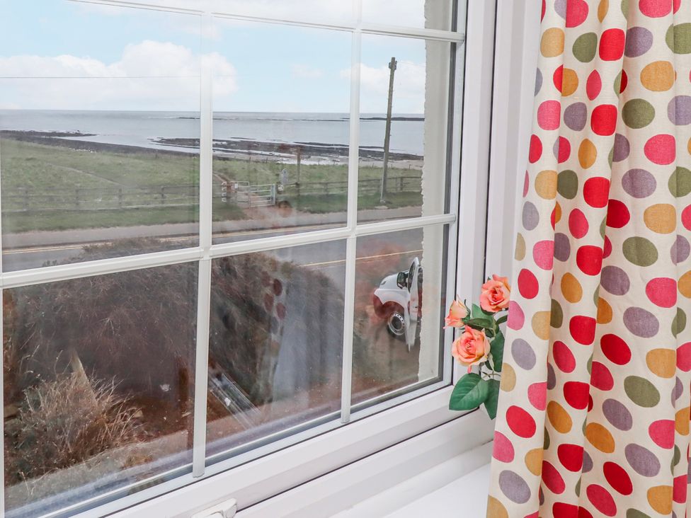 A window with a view of the sea and flowers at St Marys Cottages No4 Low Newton-by-the-Sea