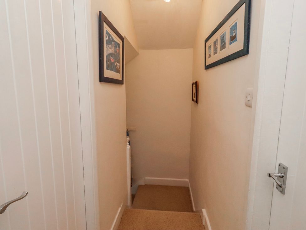 A hallway with a staircase and framed pictures at St Marys Cottages No4 Low Newton-by-the-Sea