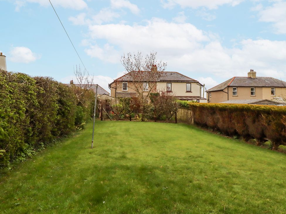 A garden with grass and houses in the background at St Marys Cottages No4 Low Newton-by-the-Sea