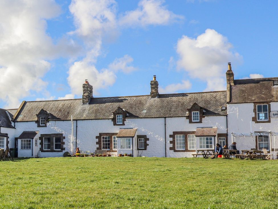 A building with windows and people sitting at a table at St Marys Cottages No4 in Low Newton-by-the-Sea