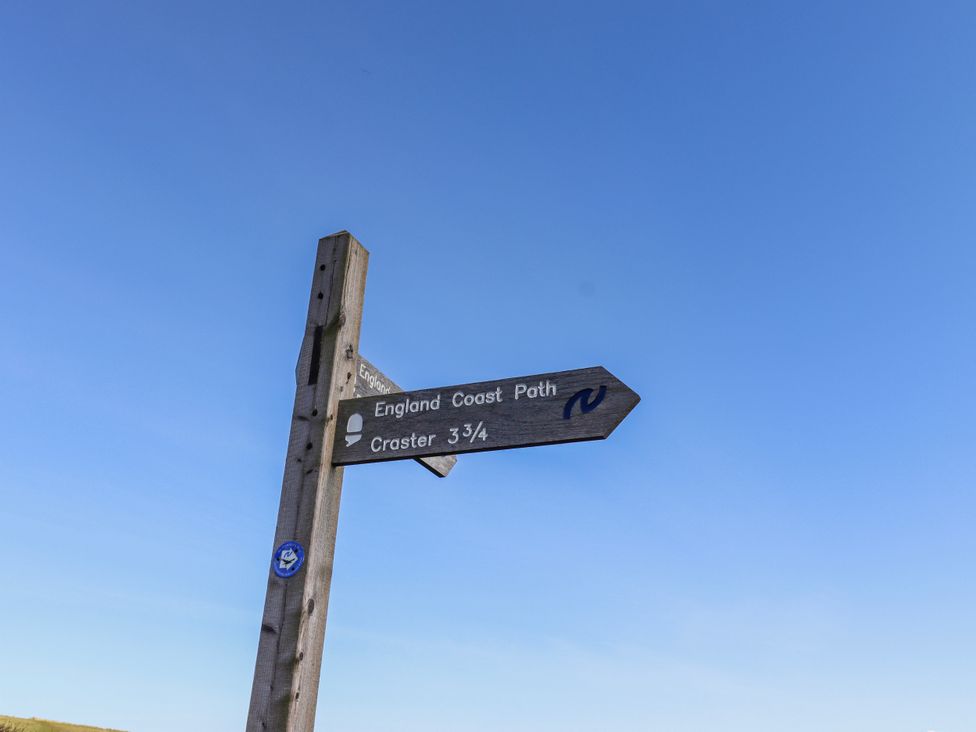 A signpost indicating England Coast Path and Craster at St Marys Cottages No4 Low Newton-by-the-Sea