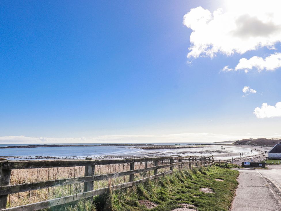 A beach with water, clouds, and a fence at St Marys Cottages No4 in Low Newton-by-the-Sea