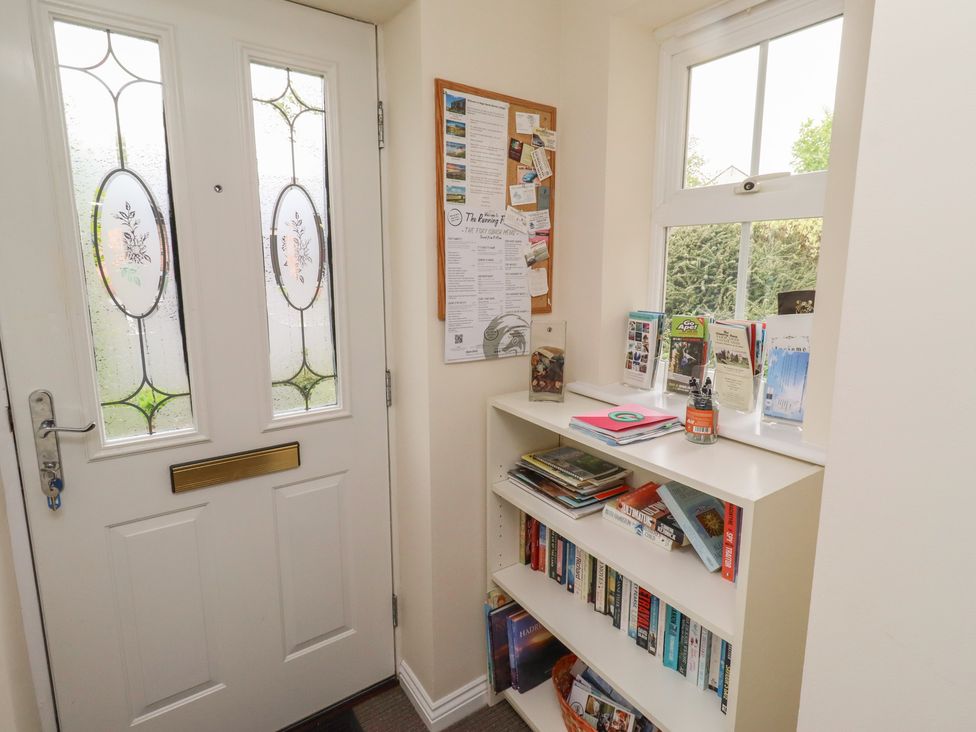 A hallway with a door and bookshelf at Sugar Sands in Longhoughton