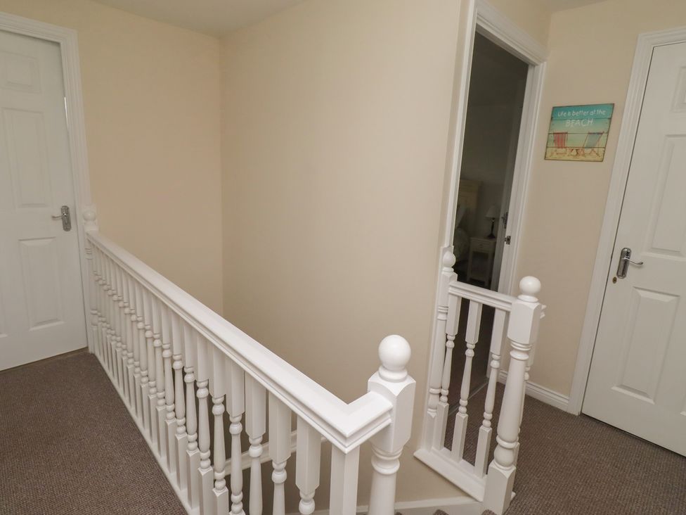 A hallway with stairs and doors at Sugar Sands Longhoughton