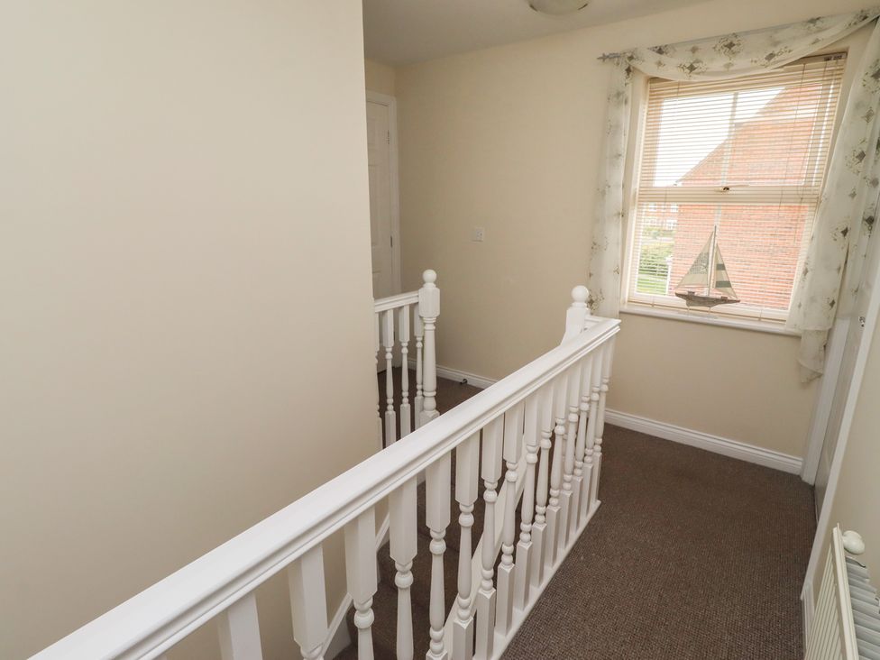 A hallway with a stair railing and a window at Sugar Sands in Longhoughton