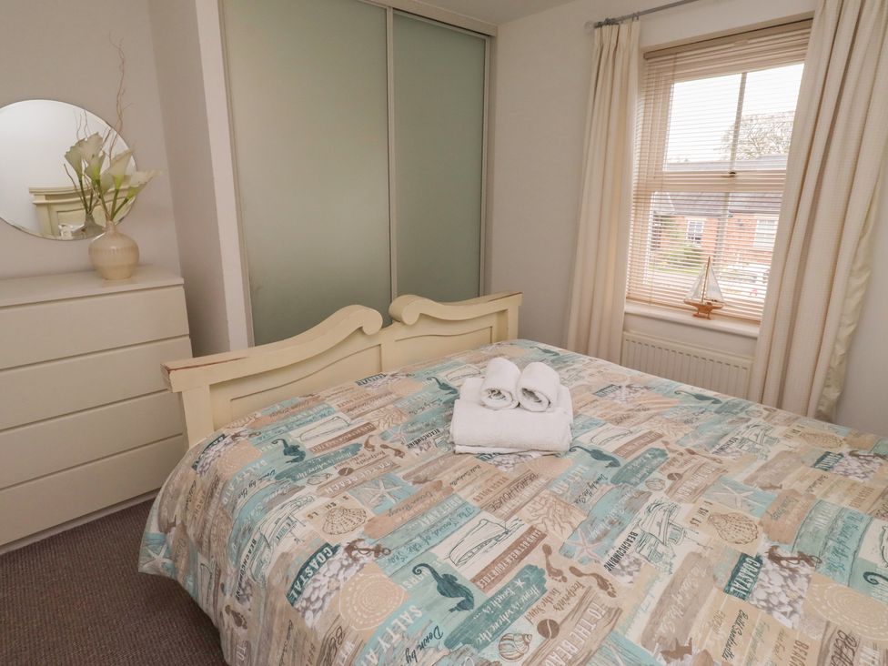 A bedroom with a bed, dresser, and towels at Sugar Sands in Longhoughton