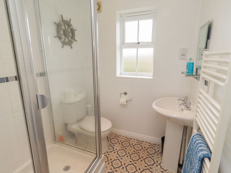 A bathroom with a shower, toilet, sink and window at Sugar Sands in Longhoughton