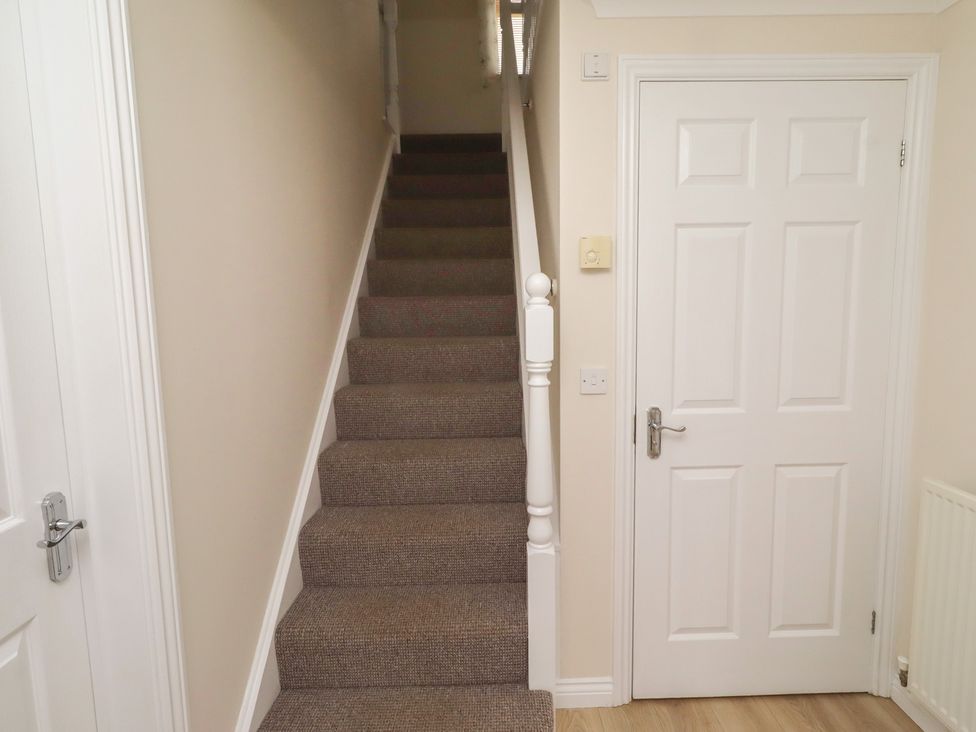 A hallway with stairs and a door at Sugar Sands in Longhoughton