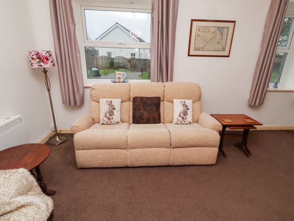 A living room with a sofa and a lamp at Wayside Cottage in Newton-by-the-Sea