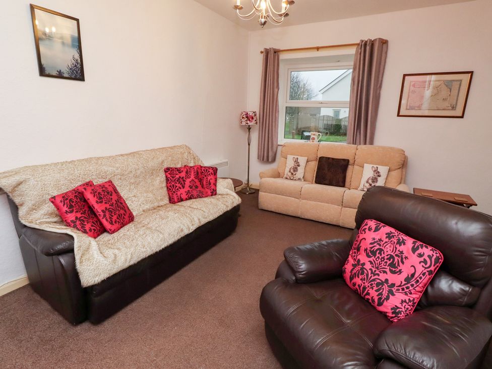 A living room with sofas and a lamp at Wayside Cottage in Newton-by-the-Sea