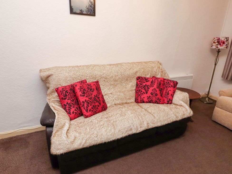 A living room with a sofa and a lamp at Wayside Cottage in Newton-by-the-Sea
