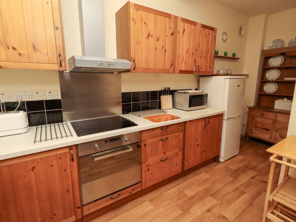A kitchen with cabinets and appliances at Wayside Cottage in Newton-by-the-Sea