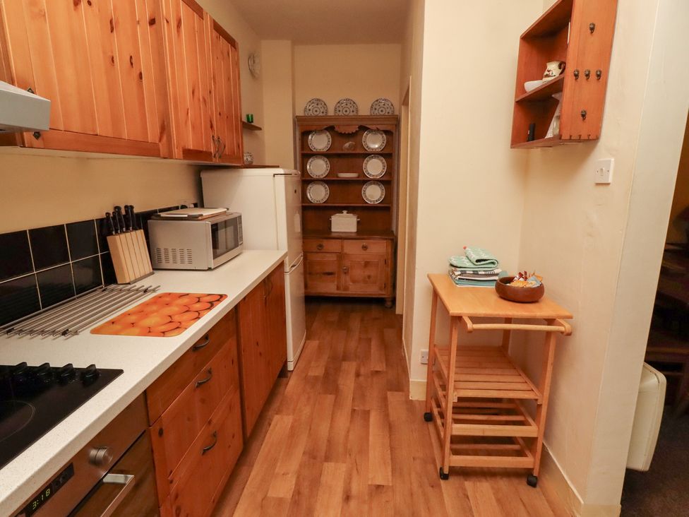 A kitchen with wooden cabinets and appliances at Wayside Cottage in Newton-by-the-Sea