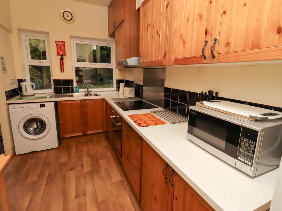 A kitchen with a washing machine and a microwave at Wayside Cottage in Newton-by-the-Sea